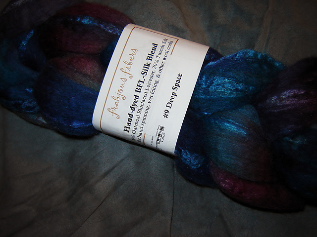 Unspun wool in dark blues, purples, reds, and greens with a shimmer.